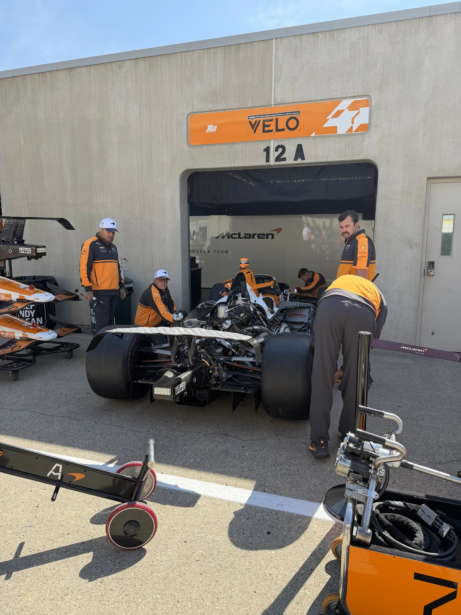 McLaren Velo pit garage 12A with crew prepping the IndyCar inside the open bay