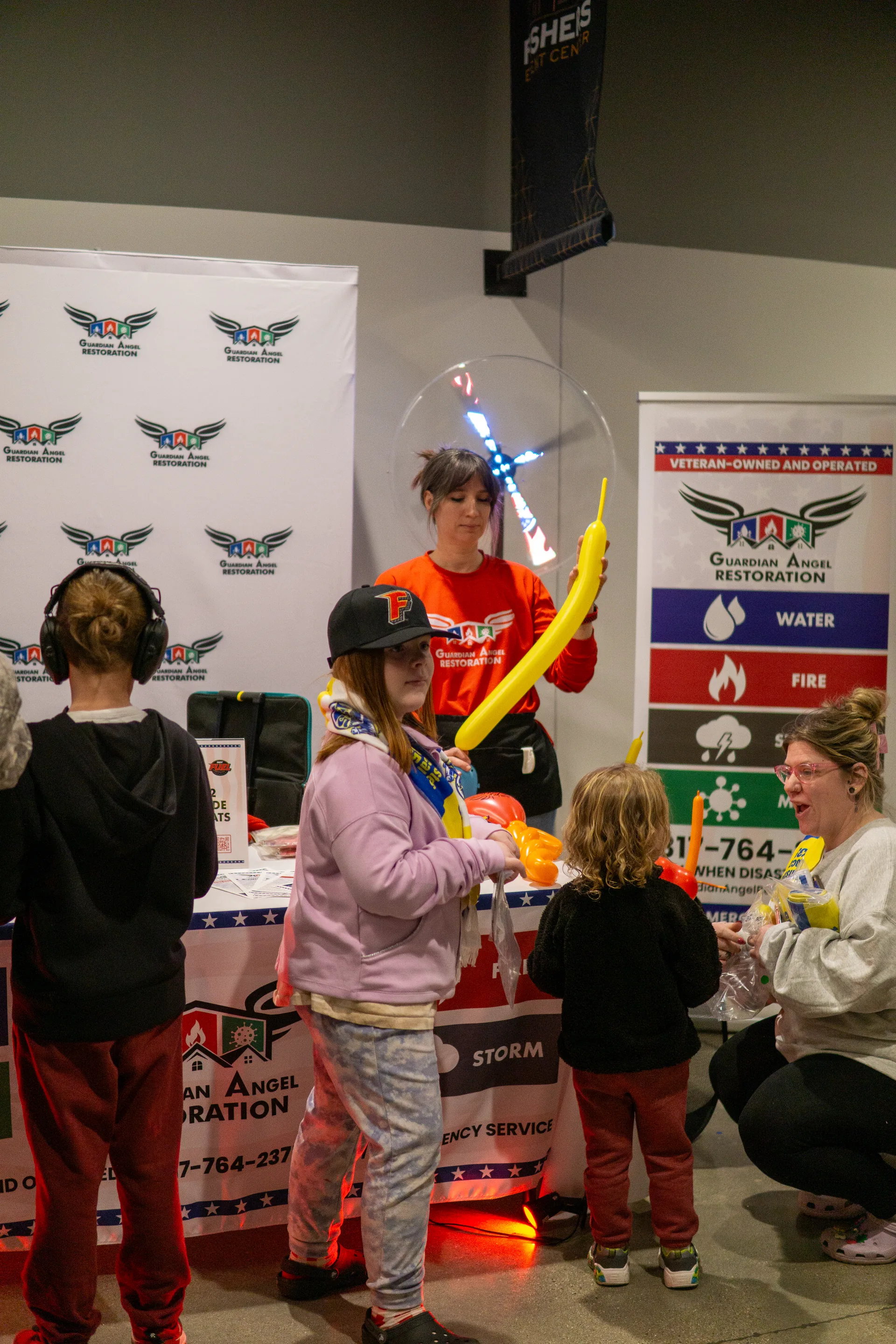 Kids holding orange balloon swords made by Guardian Angel crew