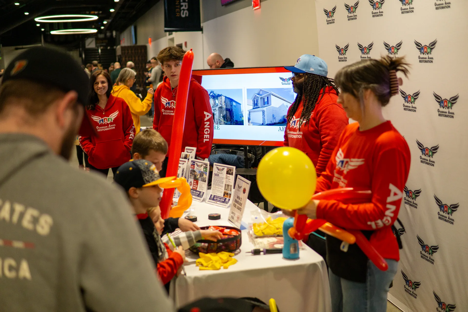 Guardian Angel Restoration crew in red hoodies at their booth before the Indy Fuel game