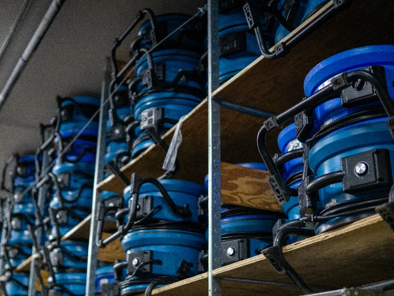 Industrial blue commercial air movers and structural drying fans stacked on shelving inside the Guardian Angel Restoration Noblesville equipment warehouse, staged for commercial property dispatch