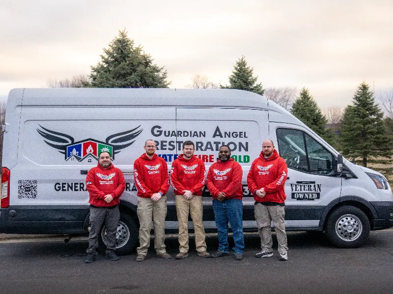 Michael Talbot and the Guardian Angel Restoration crew of five technicians in red branded hoodies standing in front of a white service van outside their Noblesville, Indiana headquarters