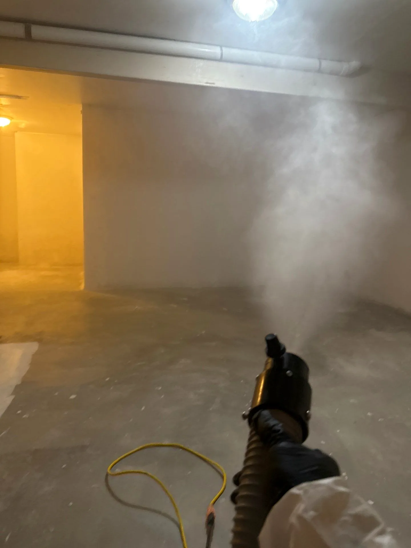 Antimicrobial fog being applied across a basement during mold remediation.