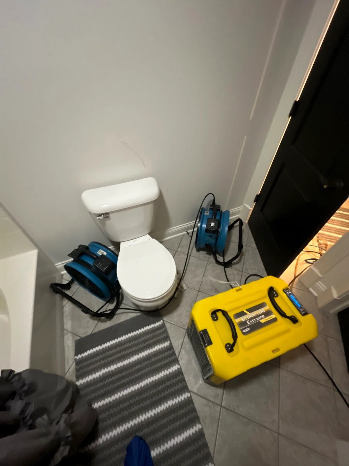 Air movers and an LGR dehumidifier packed into a bathroom during structural drying.