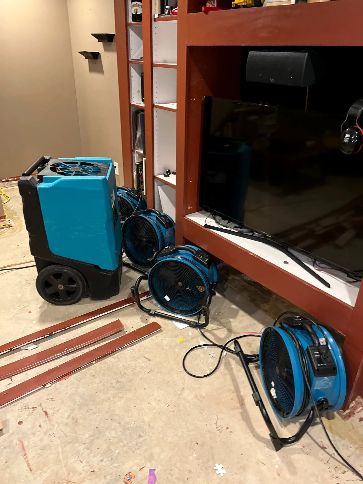 LGR dehumidifier and four air movers drying the entertainment center wall after flooring removal.