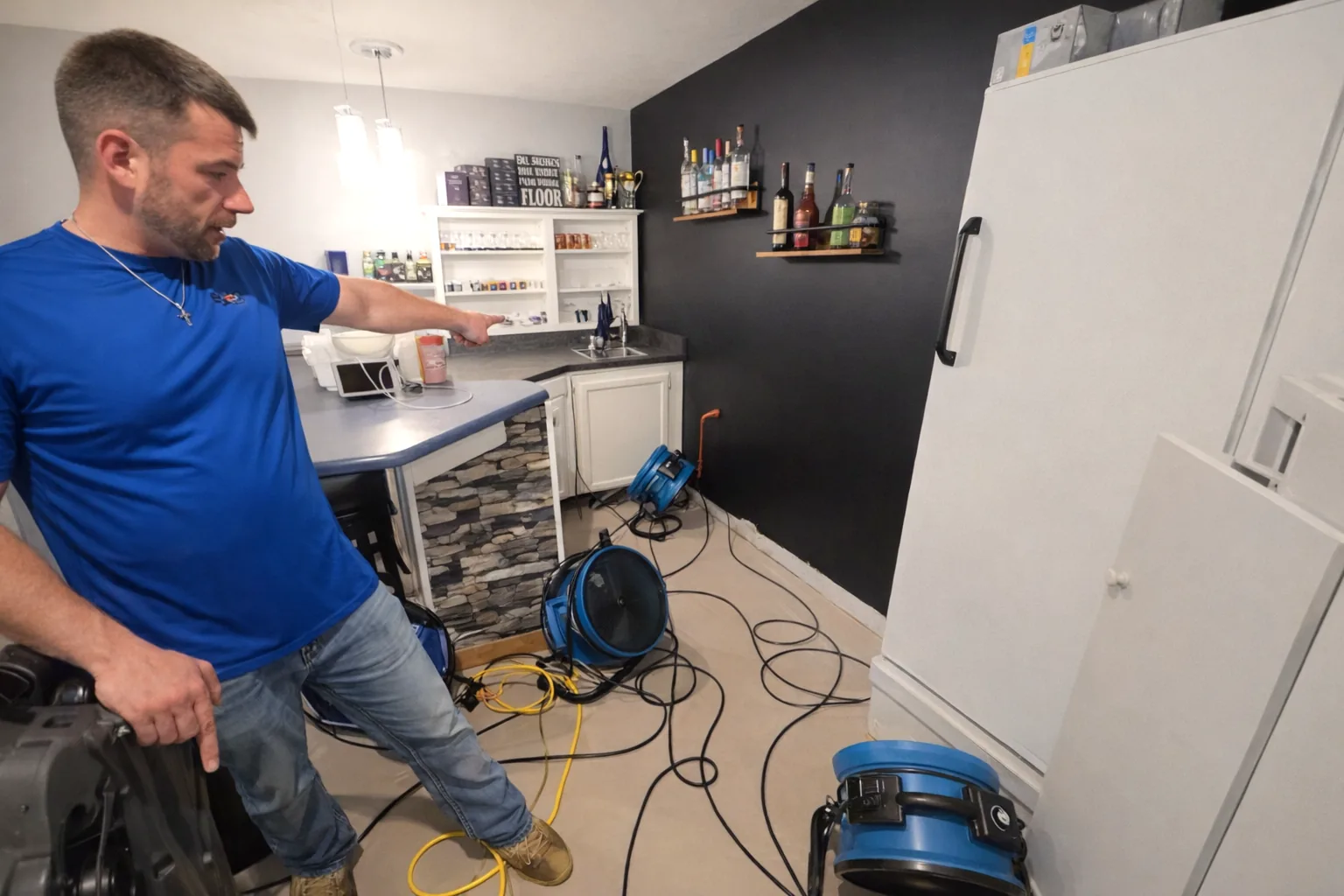Team member reviewing air mover placement around a basement bar area during drying.