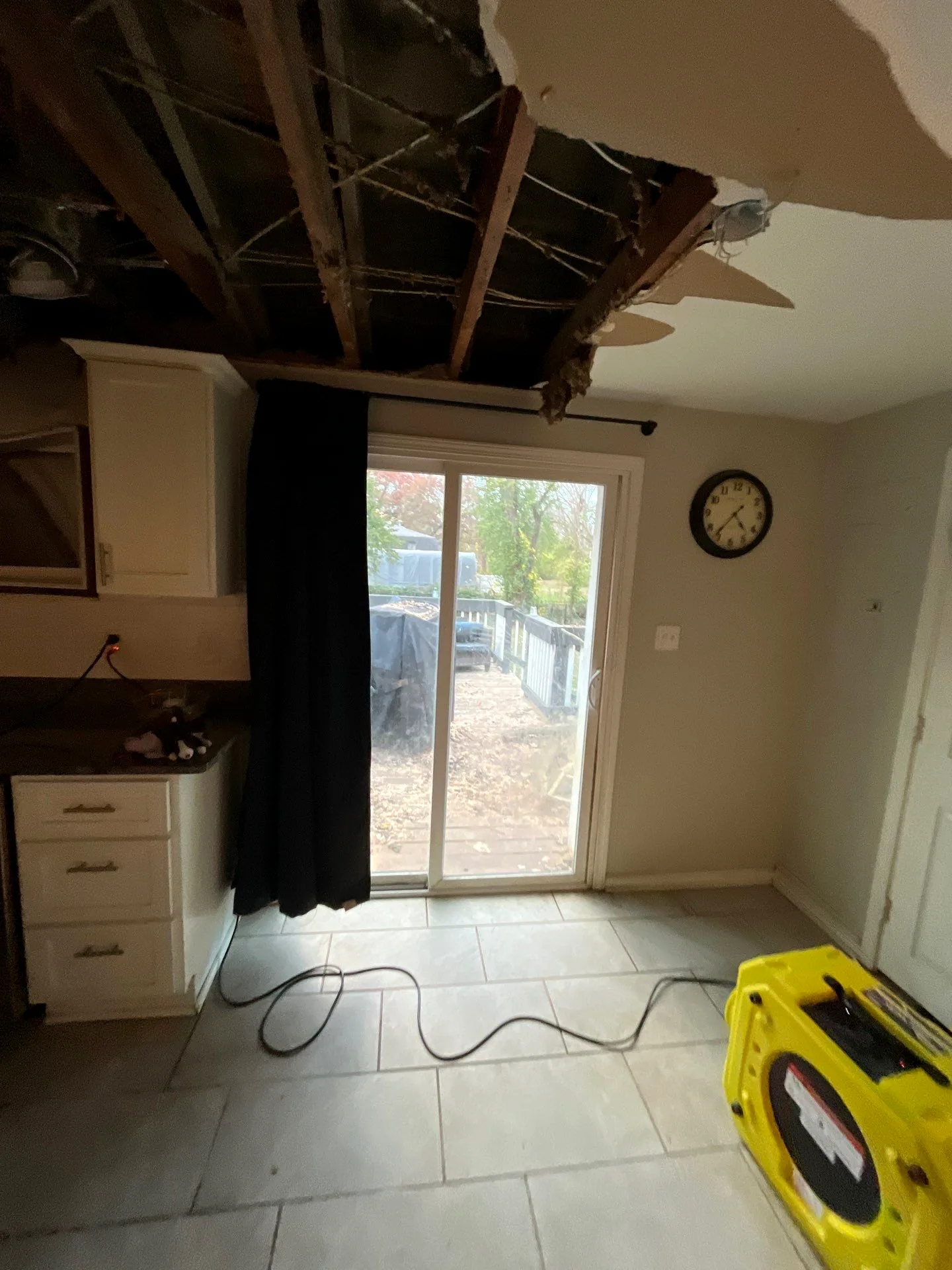 Kitchen ceiling removed to the joists above the patio door with an air mover drying the room.