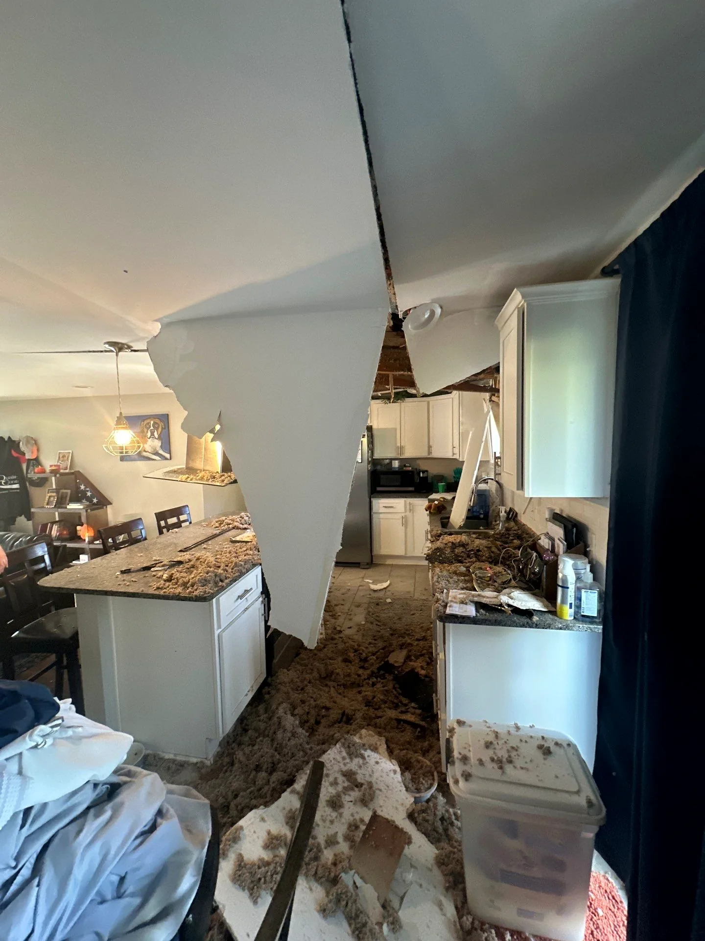Kitchen ceiling hanging in sheets with insulation piled across the counters after a storm-caused collapse.