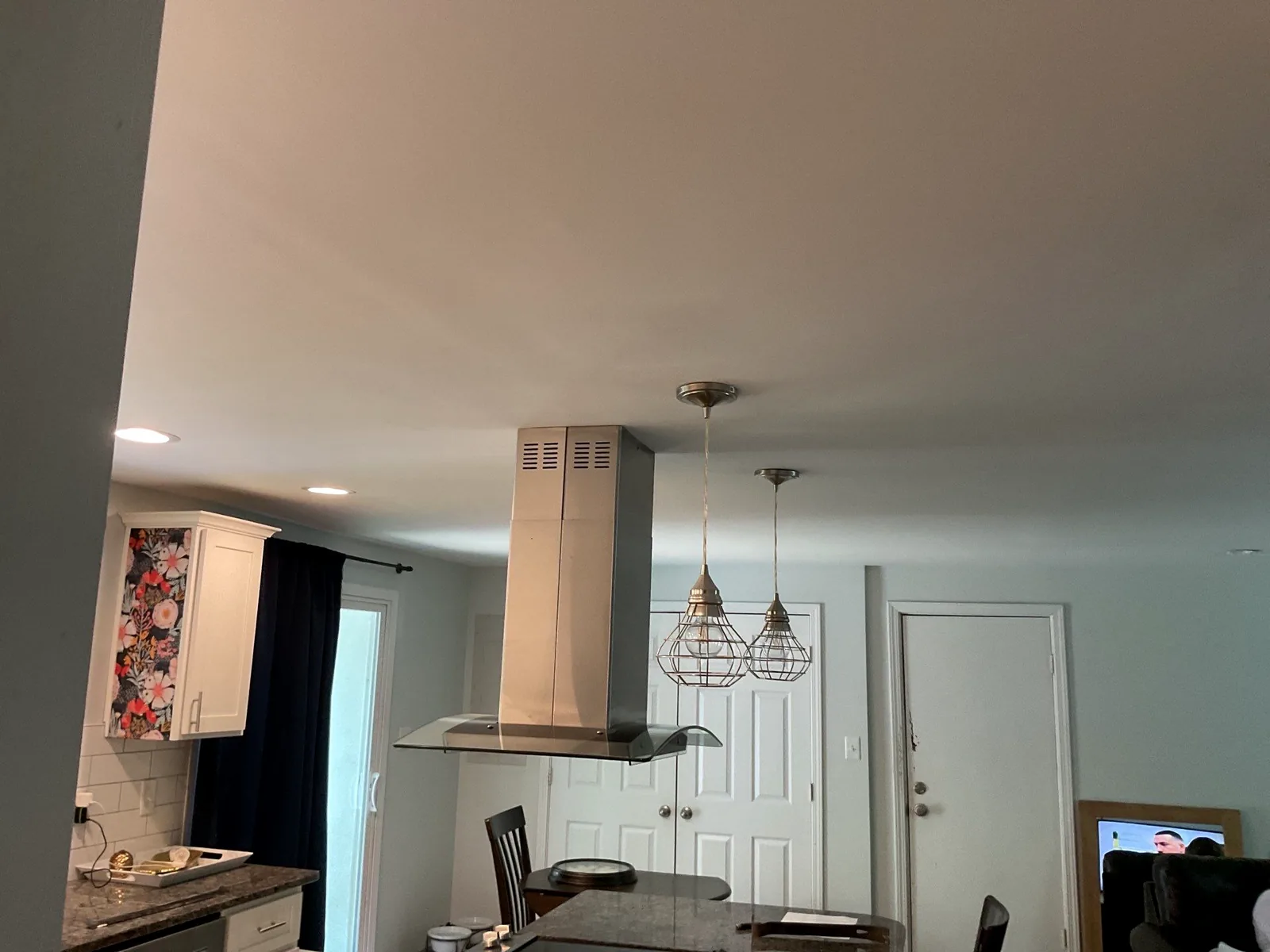 Kitchen ceiling fully rebuilt with island hood and pendant lights after storm damage repairs.